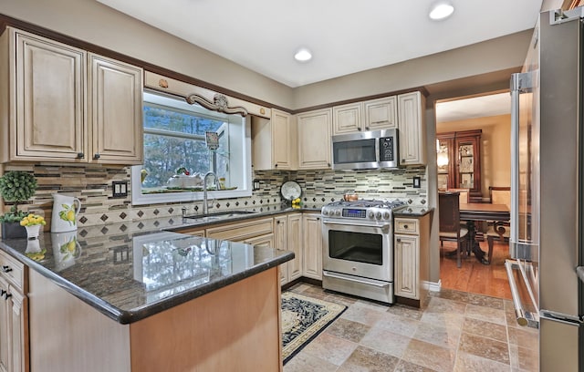 kitchen with dark stone countertops, appliances with stainless steel finishes, backsplash, and a sink