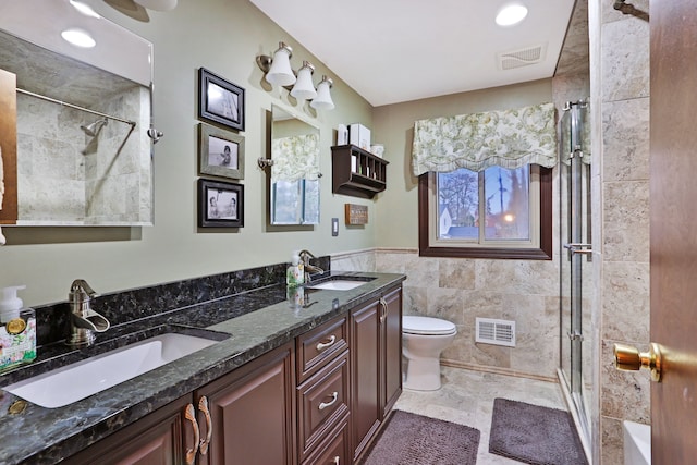 full bathroom featuring a shower stall, a sink, visible vents, and tile walls