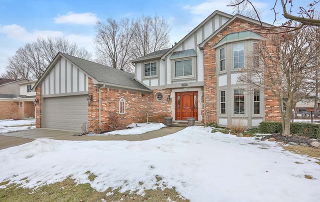 tudor home with a garage, driveway, brick siding, and a shingled roof