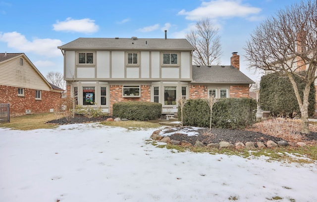 view of front of home featuring a shingled roof, brick siding, a chimney, and stucco siding