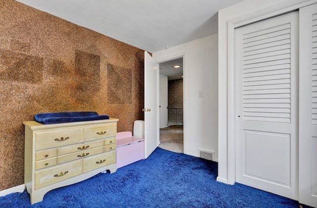 unfurnished bedroom with baseboards, visible vents, dark colored carpet, and a closet