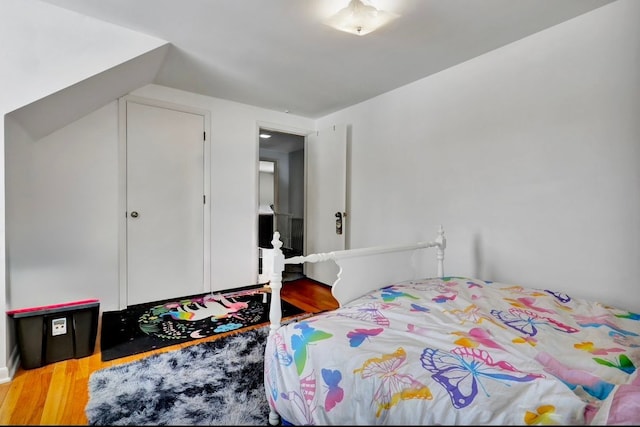 bedroom with vaulted ceiling and wood finished floors