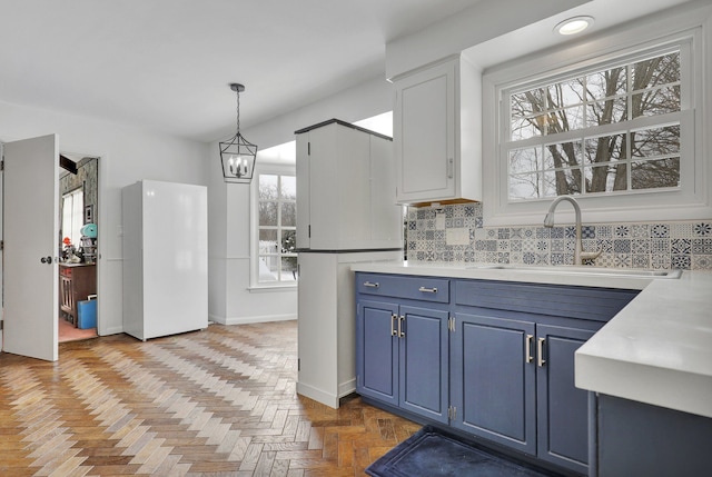 kitchen featuring light countertops, hanging light fixtures, blue cabinetry, and a sink