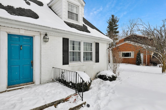 snow covered property entrance with brick siding