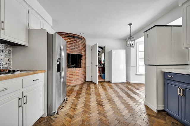 kitchen featuring decorative backsplash, white cabinets, blue cabinets, hanging light fixtures, and light countertops