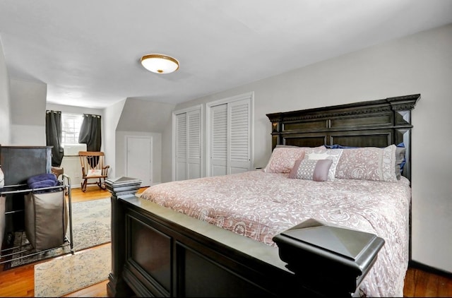 bedroom featuring light wood finished floors and multiple closets