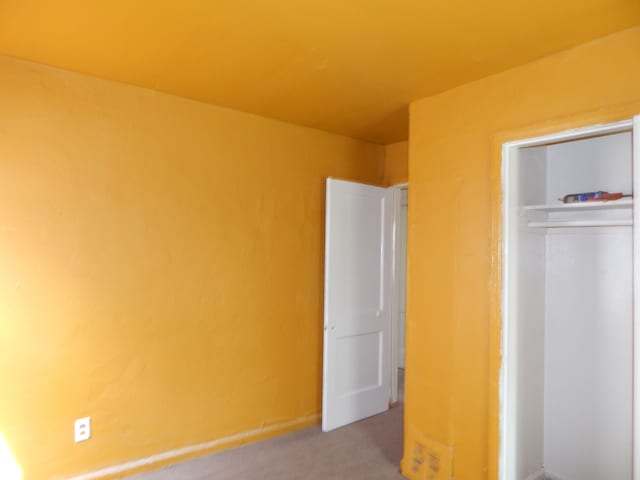 unfurnished bedroom featuring a closet and light colored carpet