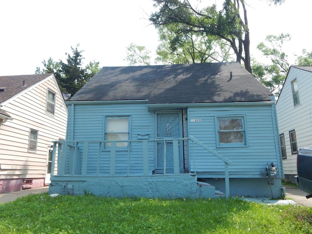 rear view of property featuring a yard and roof with shingles