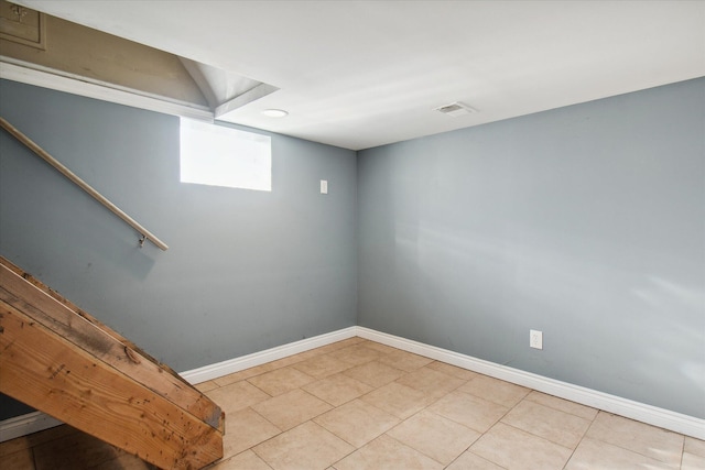 basement featuring stairs, light tile patterned flooring, visible vents, and baseboards