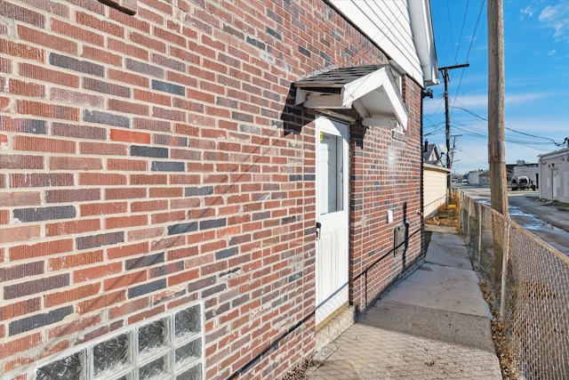 view of side of home featuring brick siding and fence