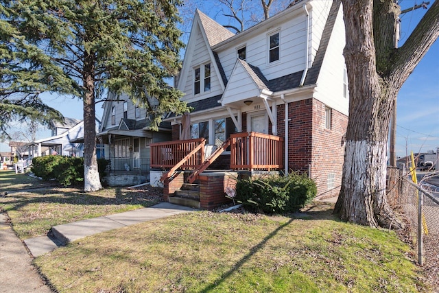 bungalow-style home featuring a shingled roof, a front yard, fence, and brick siding