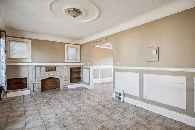 unfurnished living room with light tile patterned floors, visible vents, arched walkways, a textured ceiling, and a fireplace