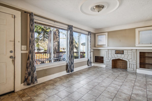 unfurnished living room featuring light tile patterned floors, baseboards, a textured ceiling, and a stone fireplace