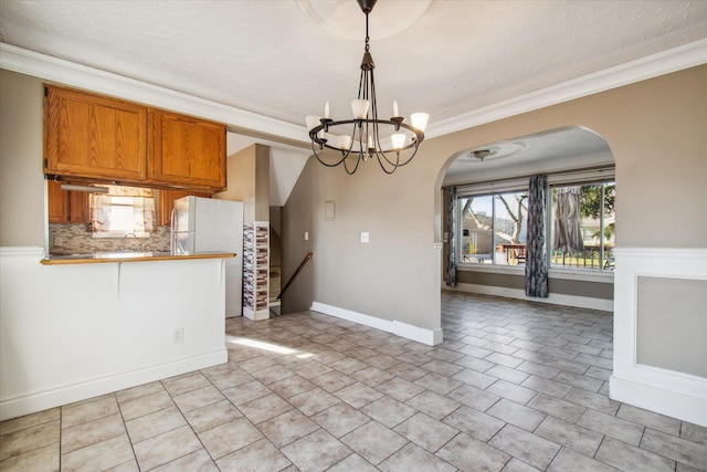 unfurnished dining area with light tile patterned flooring, crown molding, and an inviting chandelier