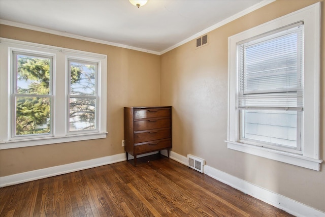 empty room featuring a healthy amount of sunlight, baseboards, visible vents, and dark wood-style flooring