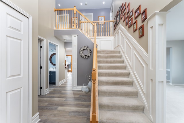 stairs featuring baseboards, a high ceiling, and wood finished floors