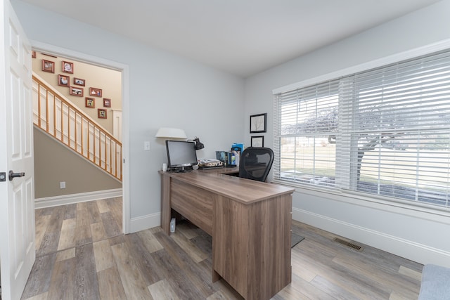 office area with wood finished floors, visible vents, and baseboards