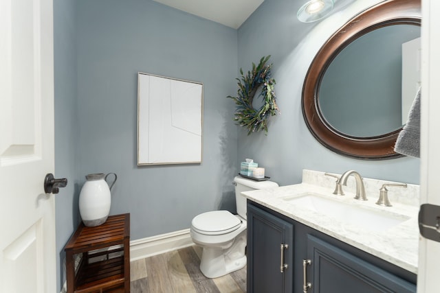 half bath featuring toilet, baseboards, wood finished floors, and vanity