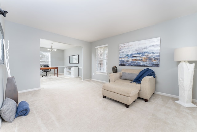 living area featuring baseboards, an inviting chandelier, and light colored carpet