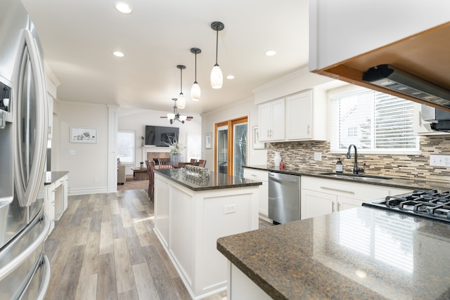 kitchen featuring stainless steel appliances, decorative backsplash, a sink, a kitchen island, and light wood-type flooring