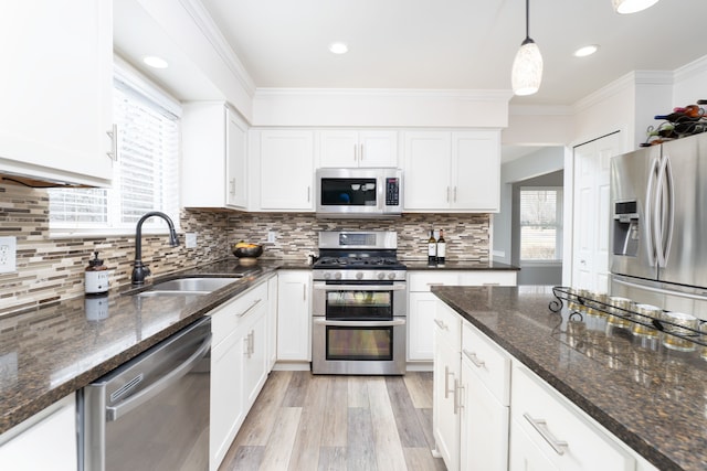 kitchen with stainless steel appliances, white cabinets, crown molding, and a sink