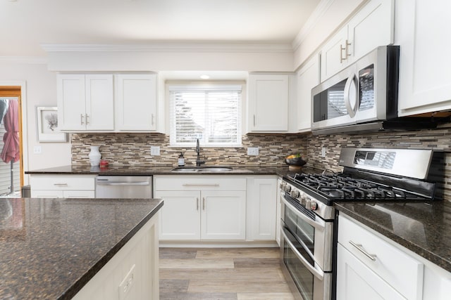 kitchen with crown molding, tasteful backsplash, appliances with stainless steel finishes, white cabinetry, and a sink