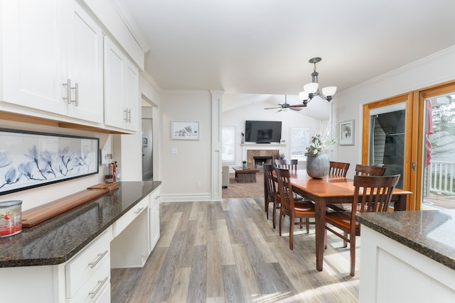 dining space with a fireplace, crown molding, lofted ceiling, light wood-style floors, and baseboards