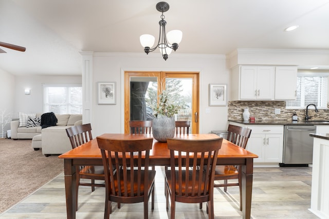 dining space featuring light wood-style floors, light carpet, ornamental molding, and an inviting chandelier