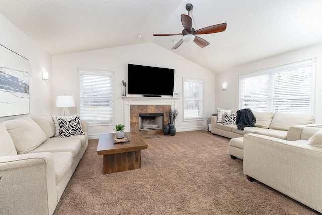 carpeted living area with baseboards, a ceiling fan, a tiled fireplace, lofted ceiling, and a textured ceiling