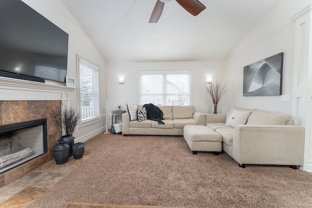 carpeted living area featuring plenty of natural light, a tile fireplace, vaulted ceiling, and a textured ceiling