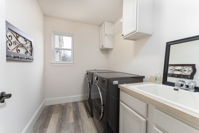 laundry area with cabinet space, a sink, wood finished floors, independent washer and dryer, and baseboards