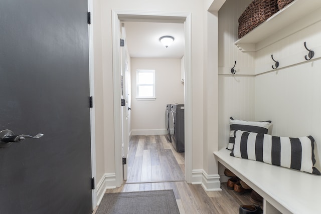 mudroom featuring baseboards, light wood finished floors, and washing machine and clothes dryer