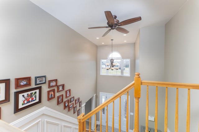 staircase with ceiling fan with notable chandelier and recessed lighting