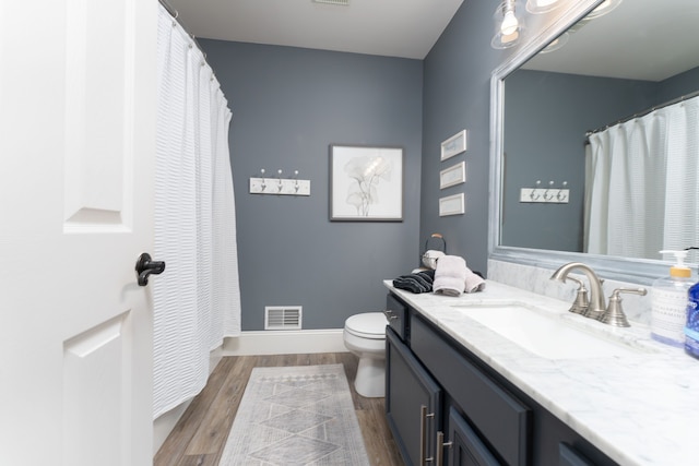 full bath featuring baseboards, visible vents, toilet, wood finished floors, and vanity