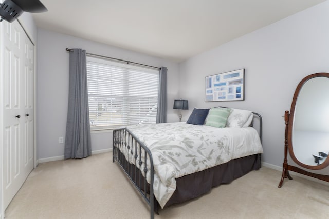 bedroom featuring a closet, light colored carpet, and baseboards