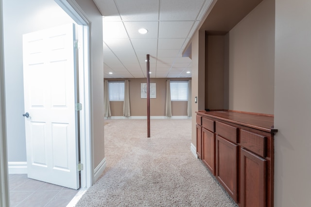 hallway with a paneled ceiling, recessed lighting, baseboards, and light colored carpet