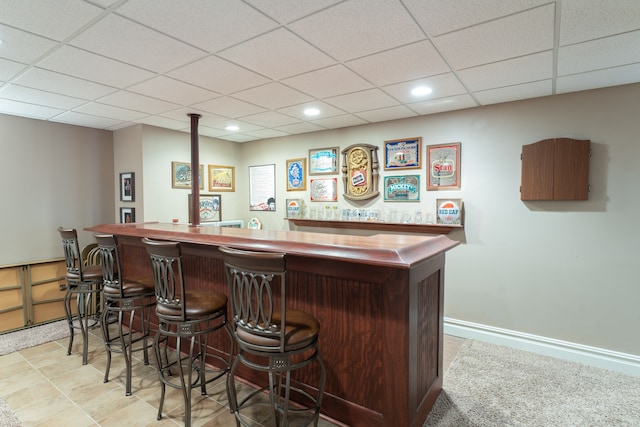 bar featuring baseboards, indoor bar, a drop ceiling, and recessed lighting