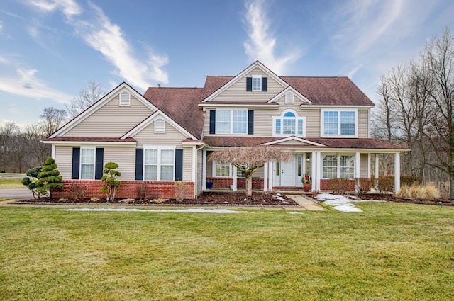 view of front of home featuring roof with shingles, a front lawn, and brick siding