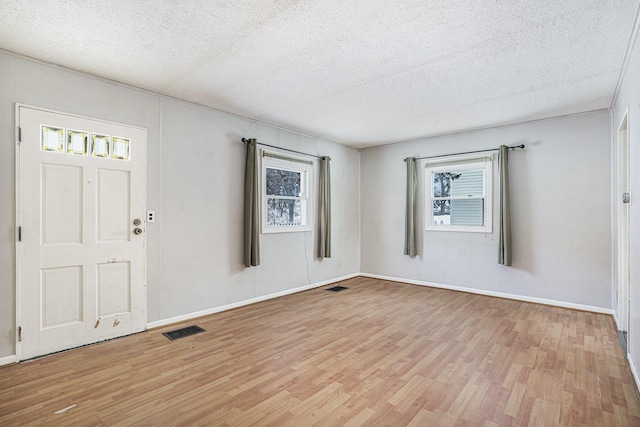 entryway with light wood finished floors, baseboards, visible vents, and a textured ceiling