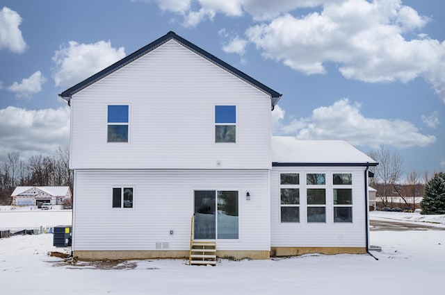 snow covered back of property featuring entry steps and cooling unit