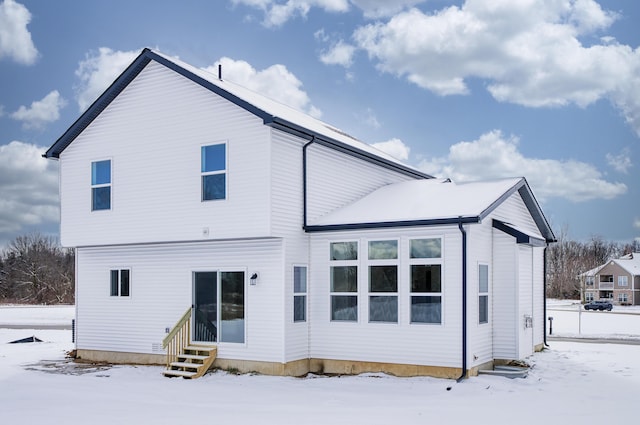 snow covered house featuring entry steps