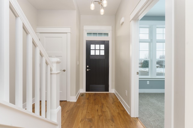 foyer entrance with light wood-style floors, a wealth of natural light, and baseboards