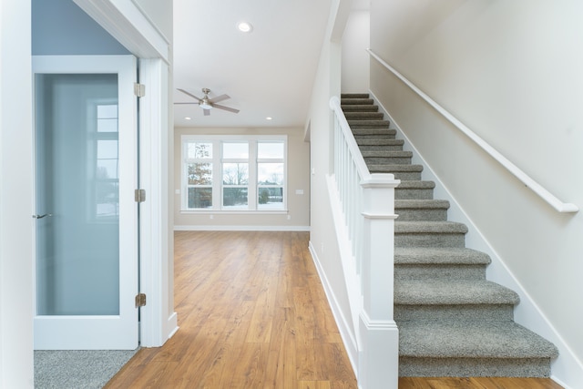 staircase featuring ceiling fan, baseboards, wood finished floors, and recessed lighting