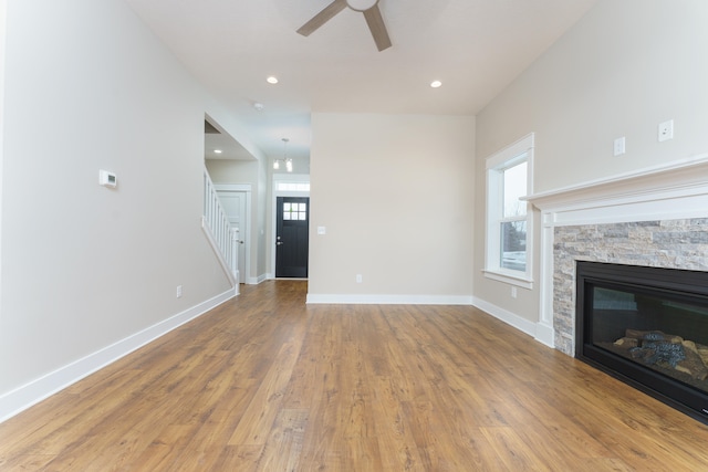 unfurnished living room with recessed lighting, baseboards, wood finished floors, and a stone fireplace