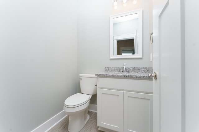 bathroom with toilet, baseboards, and vanity