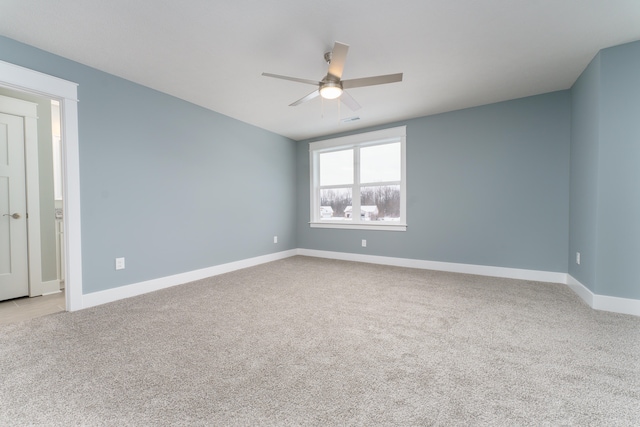 spare room featuring light carpet, visible vents, a ceiling fan, and baseboards