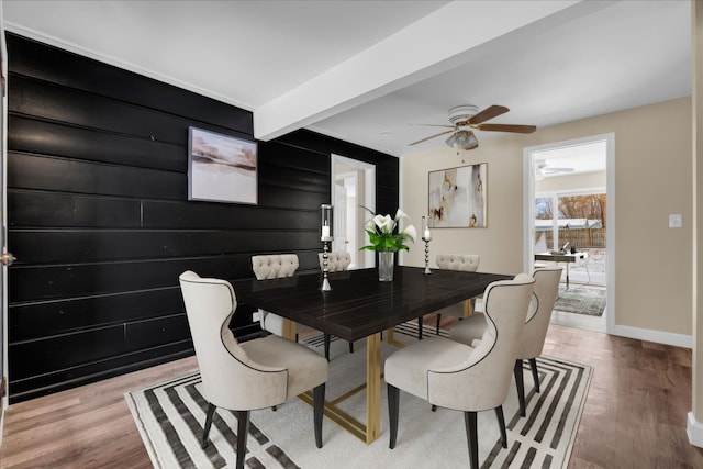 dining area featuring light wood-style floors, a ceiling fan, baseboards, and beam ceiling