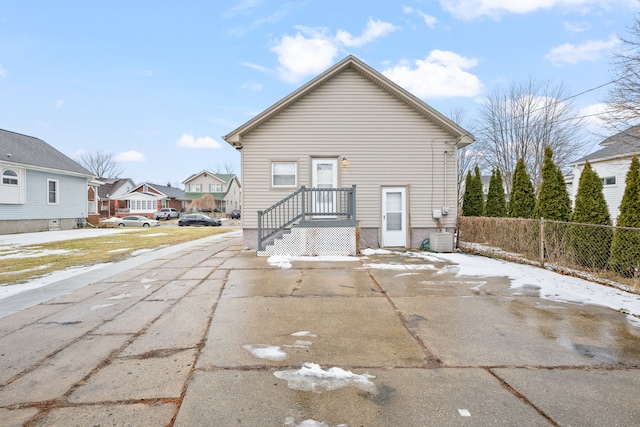 rear view of property featuring fence, a residential view, and central air condition unit