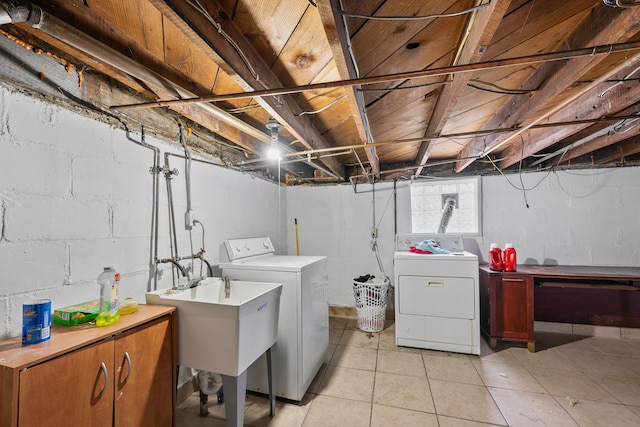 laundry area with a sink, light tile patterned flooring, washing machine and clothes dryer, and cabinet space