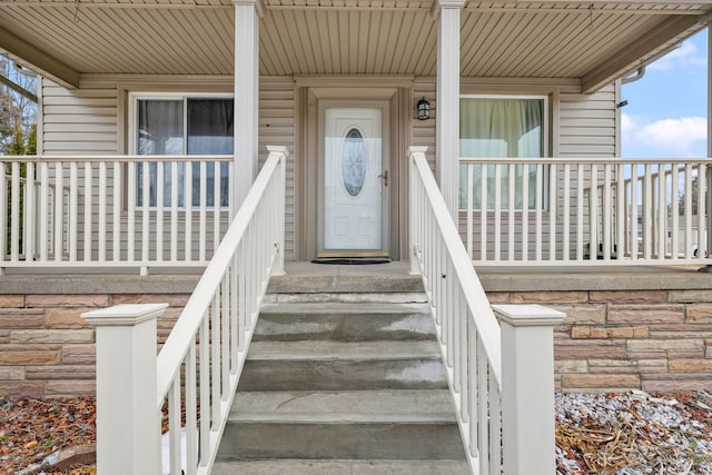 doorway to property featuring stone siding and a porch